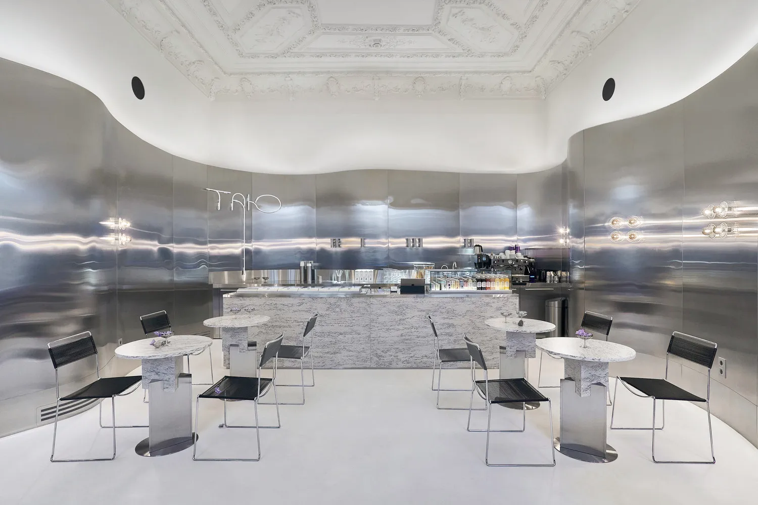 Sophisticated restaurant interior with white marble walls, wine glasses, and comfortable seating areas
