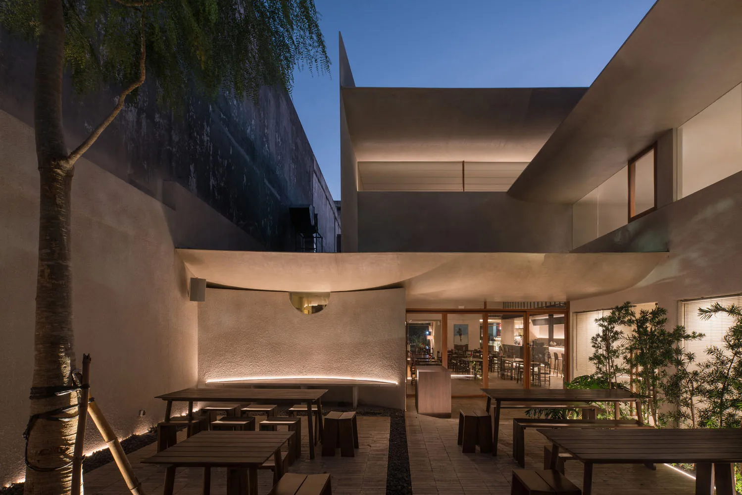 A modern restaurant interior with concrete walls, dining tables, and chairs, creating a stylish and inviting atmosphere