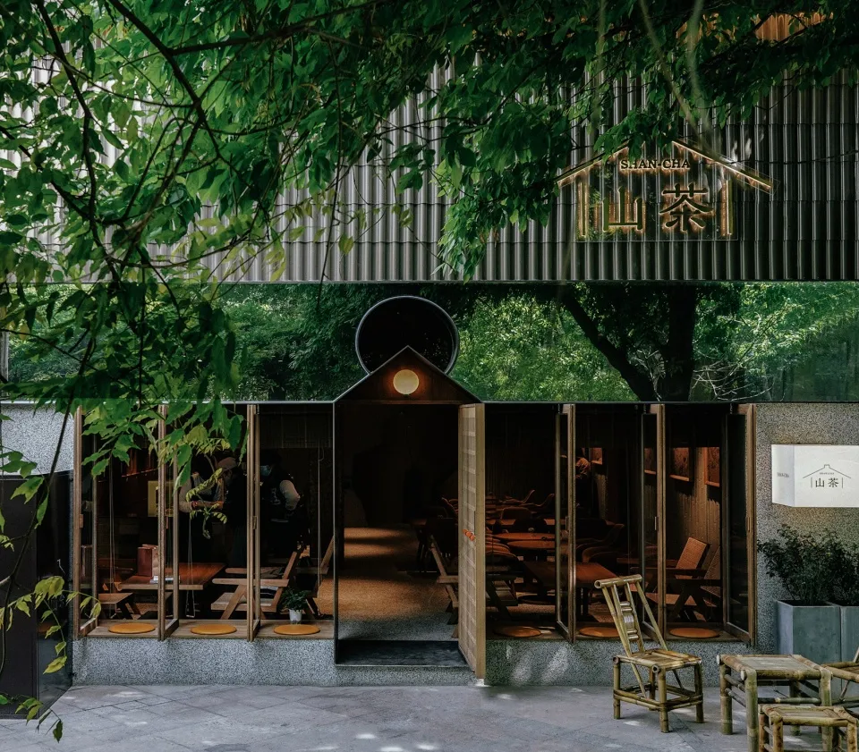 Modern Asian restaurant with a large dining area, chairs, and benches, surrounded by natural elements and well-lit interior