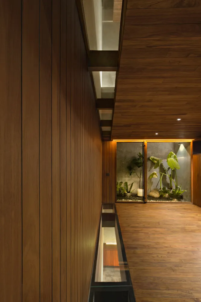 Warm and inviting indoor space with wooden walls and floors, featuring potted plants and a vase, creating a cozy ambiance