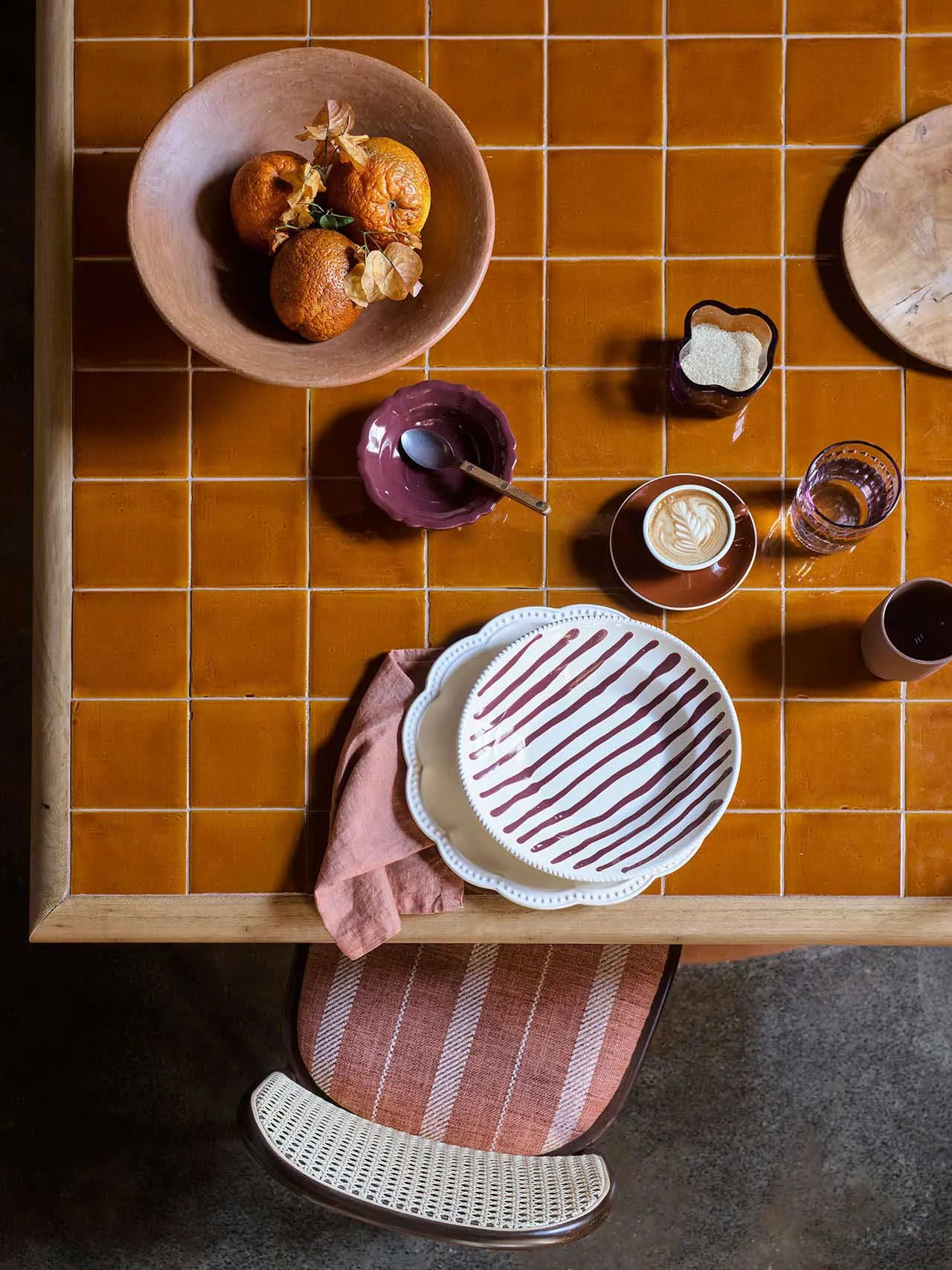 A kitchen dining area with a wooden table set up with food, cups, and apples, creating a warm and inviting atmosphere