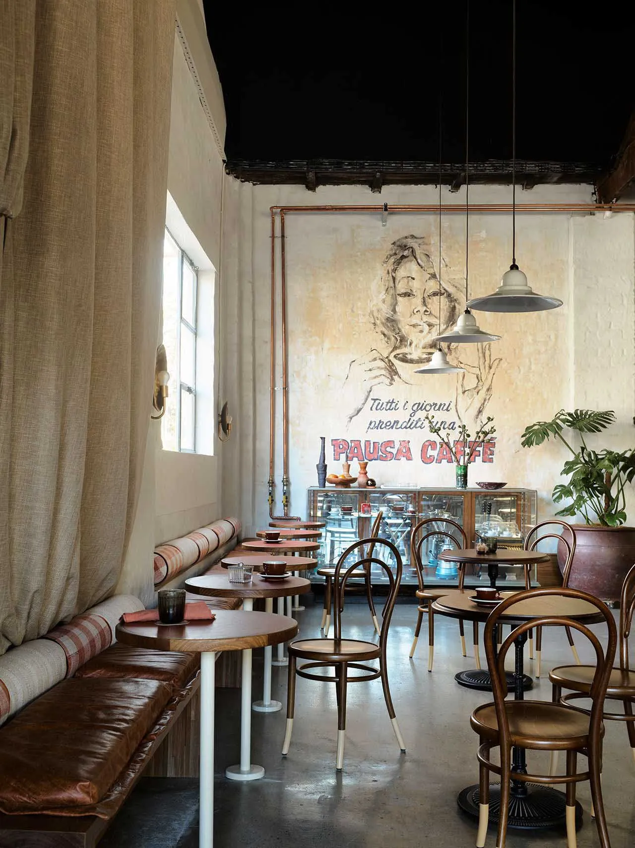 A restaurant dining area with tables, chairs, artwork on the walls, and a bar offering additional seating and a cozy atmosphere