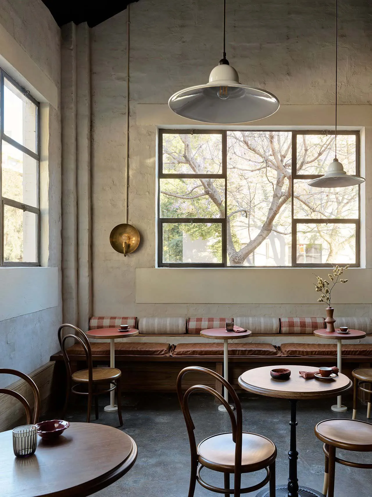 A modern cafe dining area with multiple tables and chairs, dimly lit for a cozy atmosphere, featuring vases and bowls on the tables