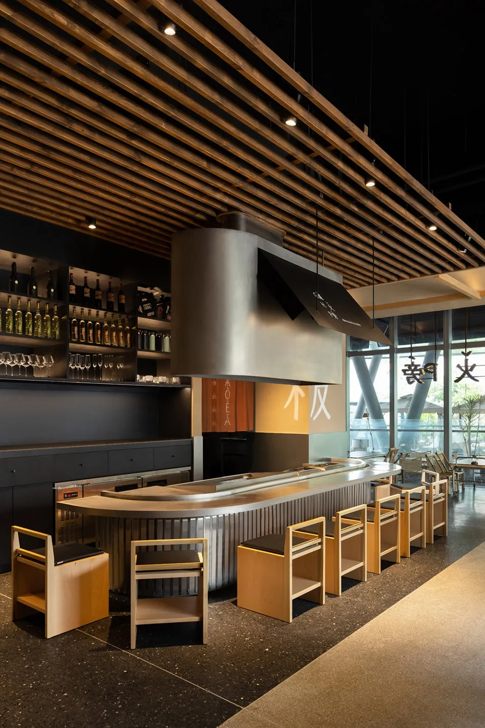 Modern Asian restaurant bar with a countertop, chairs, and bottles of various sizes displayed, creating a functional and stylish atmosphere