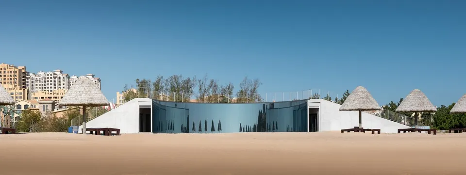 A modern house with a glass wall reflecting trees and surrounding landscape, built with concrete and featuring a sleek and contemporary design