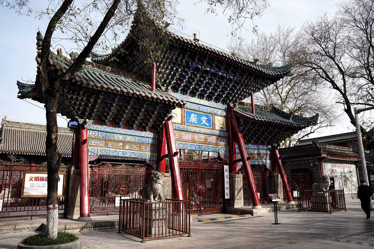 紅牆亞洲風建築，大型門廊入口，以及數尊雕像包括獅子，襯托於文化藝術背景