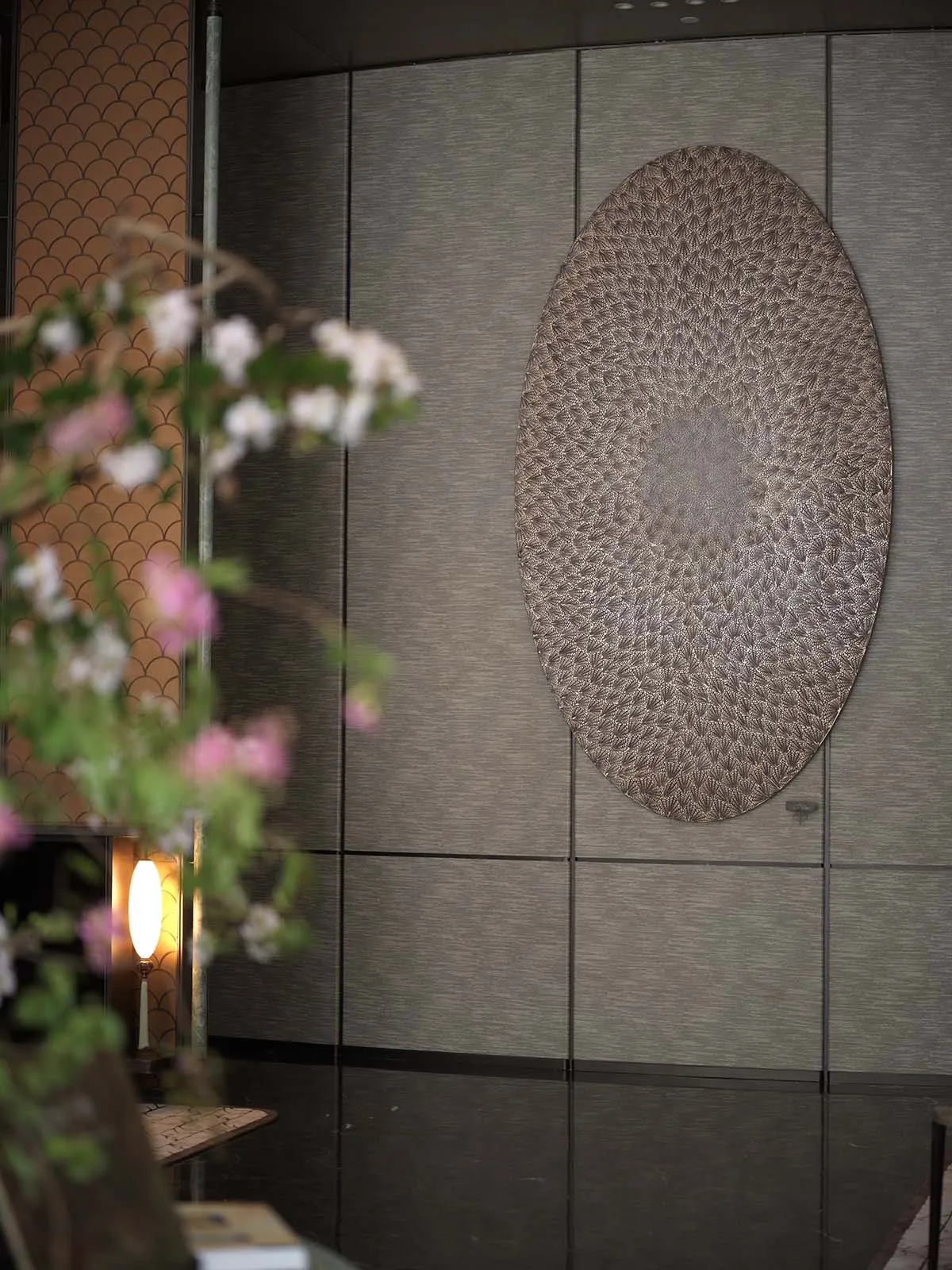 A sophisticated interior space featuring a large leather artwork mounted on a wall, surrounded by smaller decorative circles and elegant atmosphere