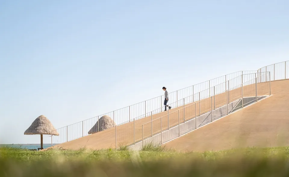 A man walks up a concrete staircase with a metal railing, surrounded by natural light and a casual atmosphere