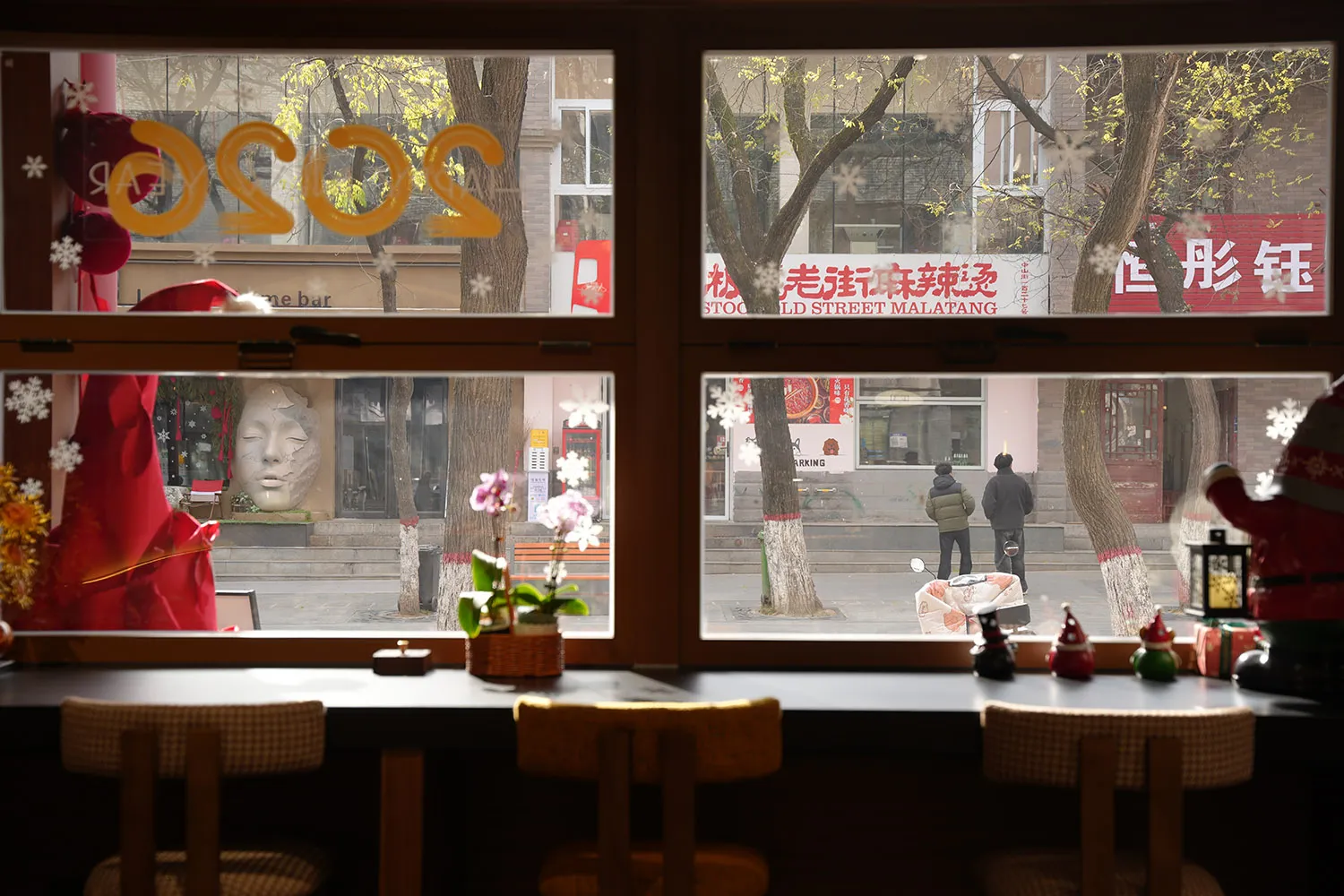Cozy restaurant interior with wooden tables and chairs, potted plants, and a variety of seating options