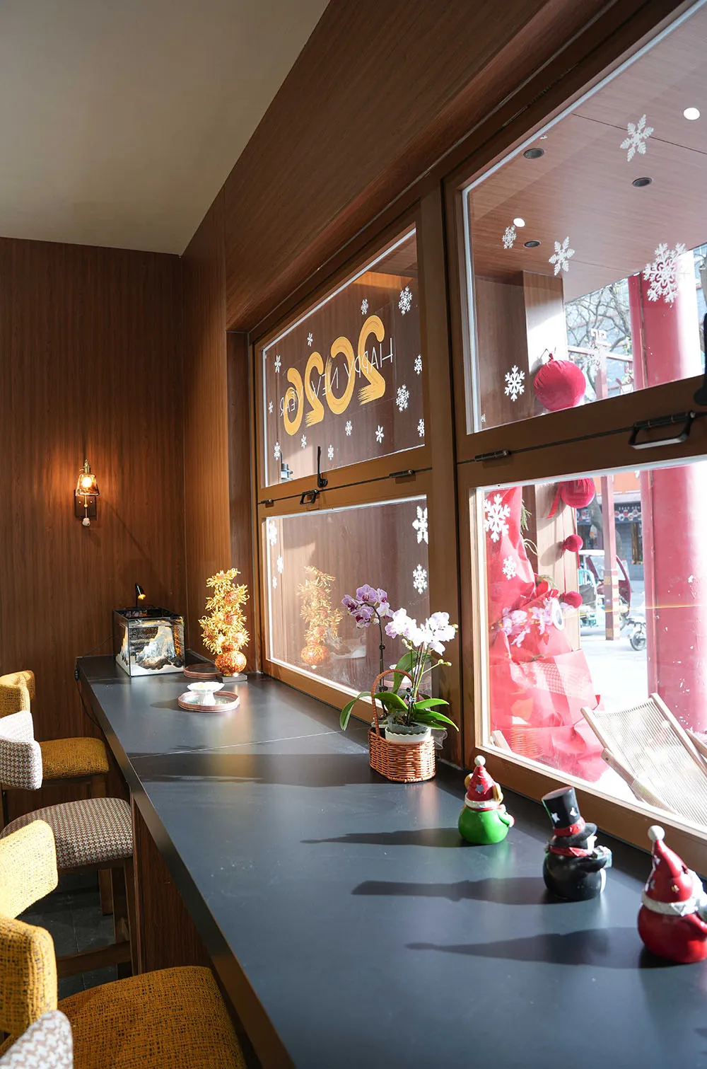 A well-lit dining area with a wooden table surrounded by chairs, featuring potted plants and various decorative items