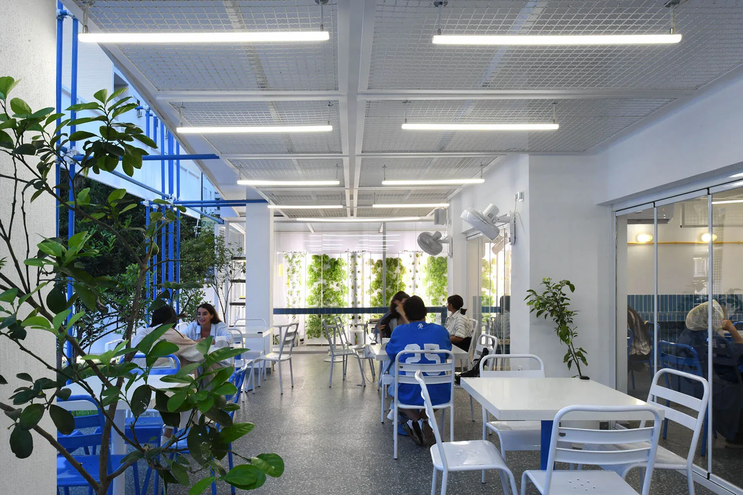 木桌椅休閒餐廳空間，周圍有人坐著站著，採光充足
