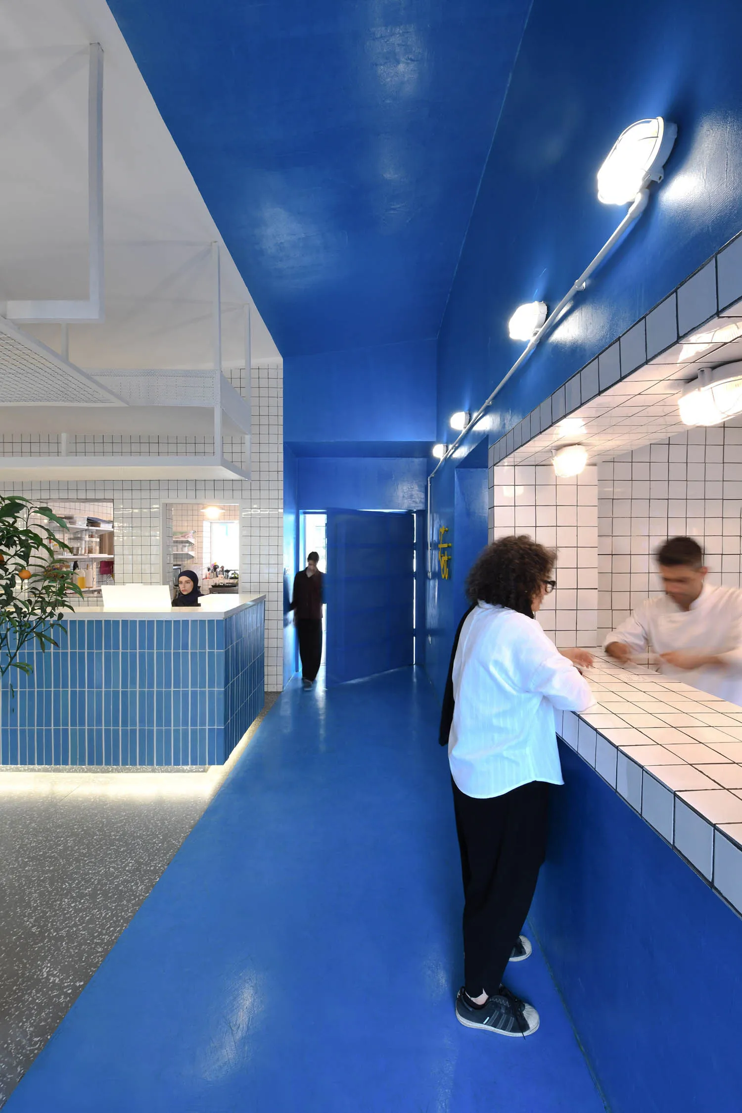 A bright and inviting hotel lobby with blue walls and floor, featuring a large open area with people socializing