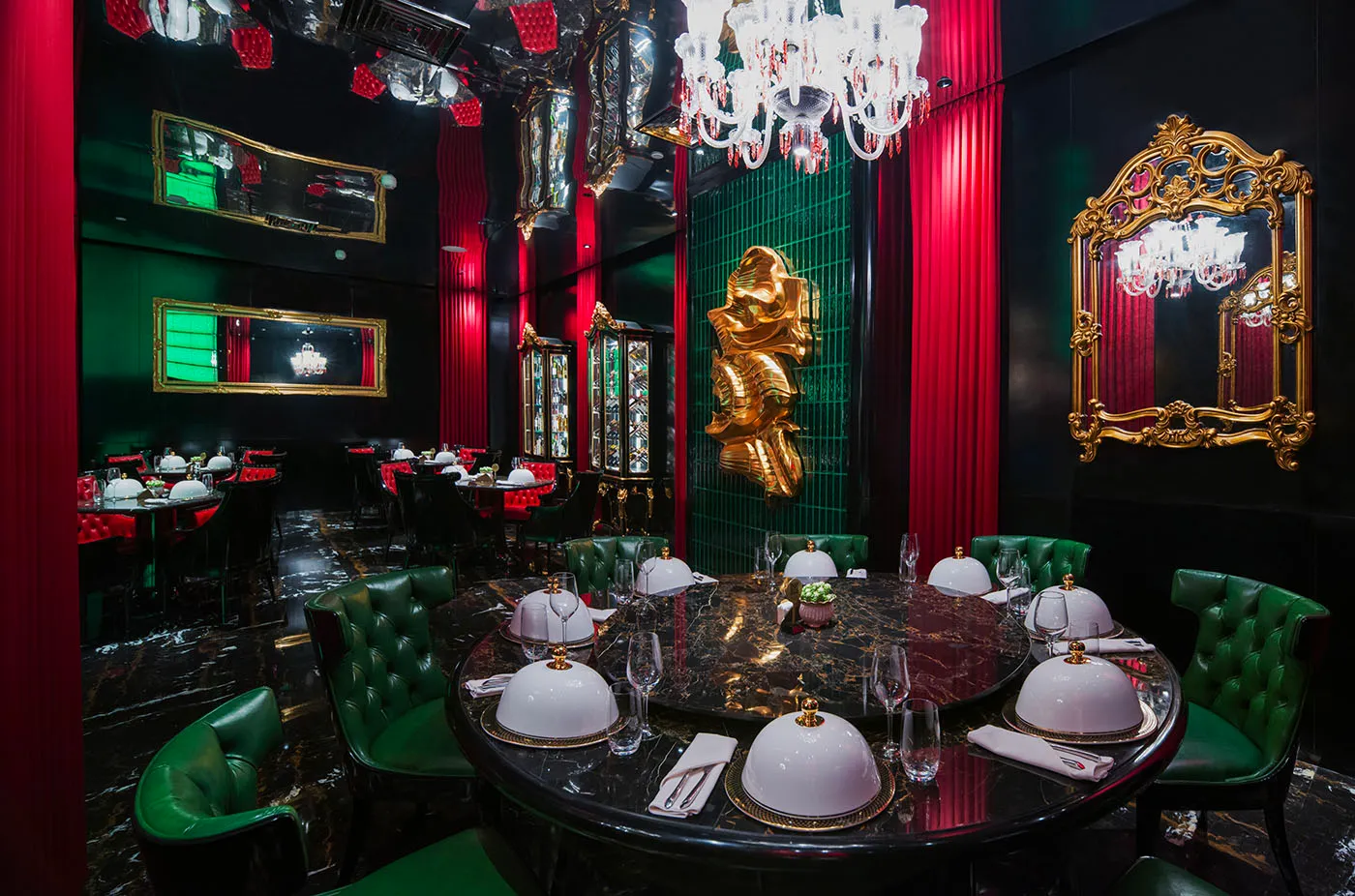 Elegant dining area with a table set for a meal, surrounded by chairs, in a room with red walls and a chandelier