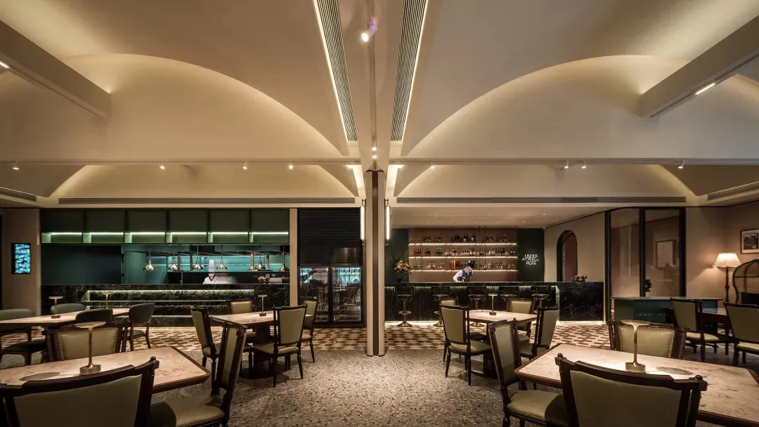 A lively restaurant interior with multiple tables, chairs, and decorative items such as bottles, vases, and potted plants, set in a modern and stylish environment