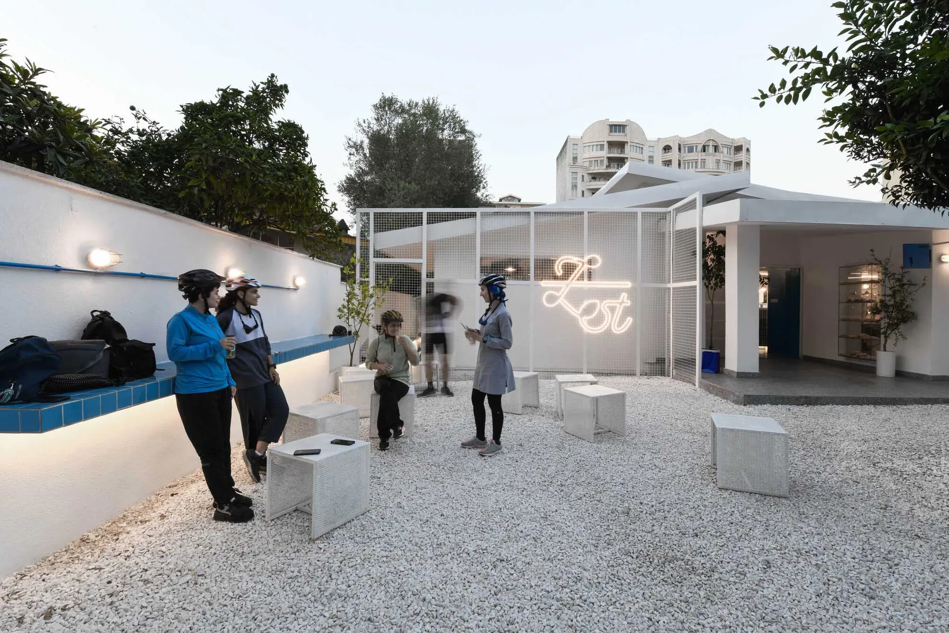 A modern indoor space with white walls, hosting a social gathering with several people standing and interacting