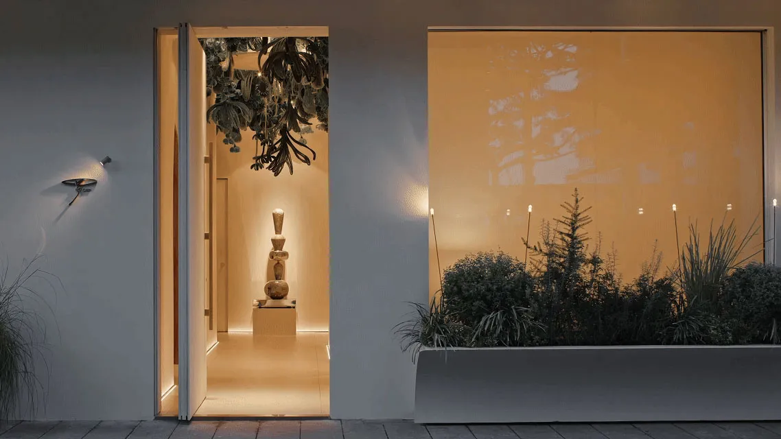 A bright and inviting room with a sculpture on display, natural light streaming in through open doors, and white doors leading to a spacious interior