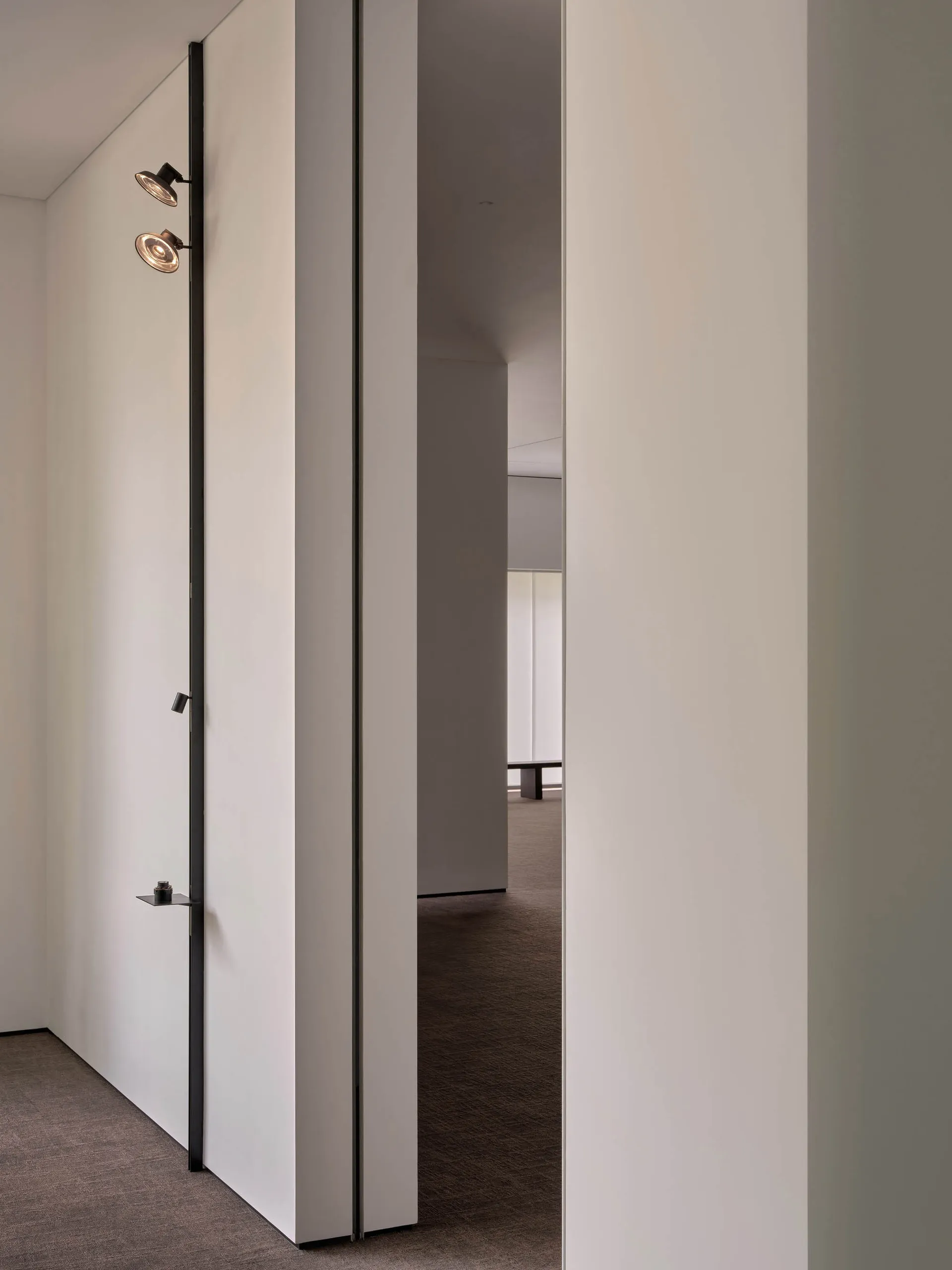 A clean and well-lit empty hallway with white walls and two doors, one on each side