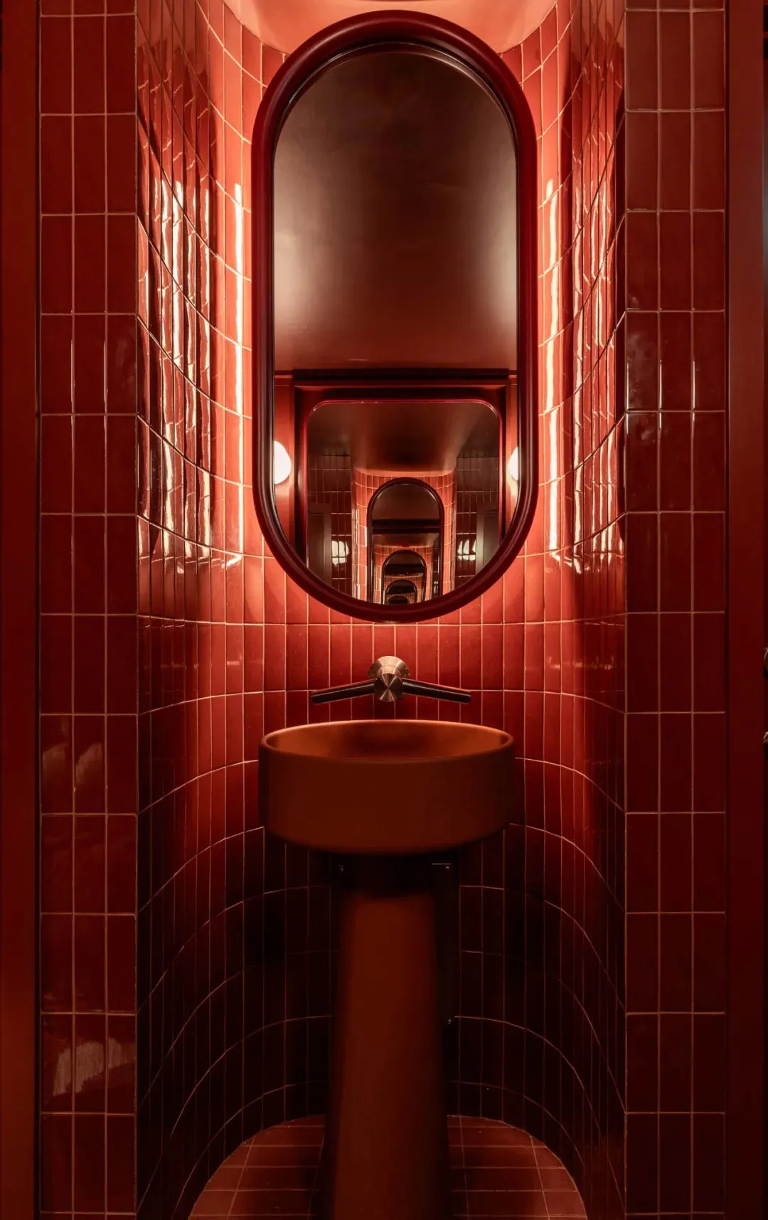 Bathroom with red walls, a metal sink, and two mirrors, creating a warm and inviting atmosphere