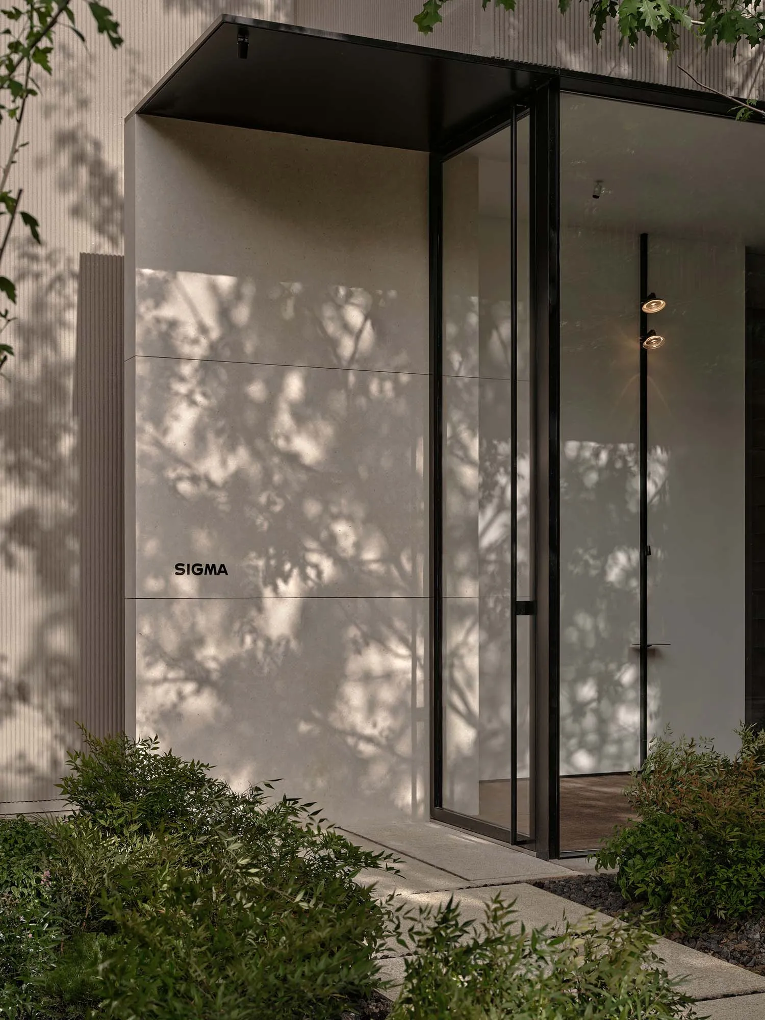 A modern indoor space with a glass door and window, featuring clean lines and minimalistic design elements, with sunlight streaming through the windows