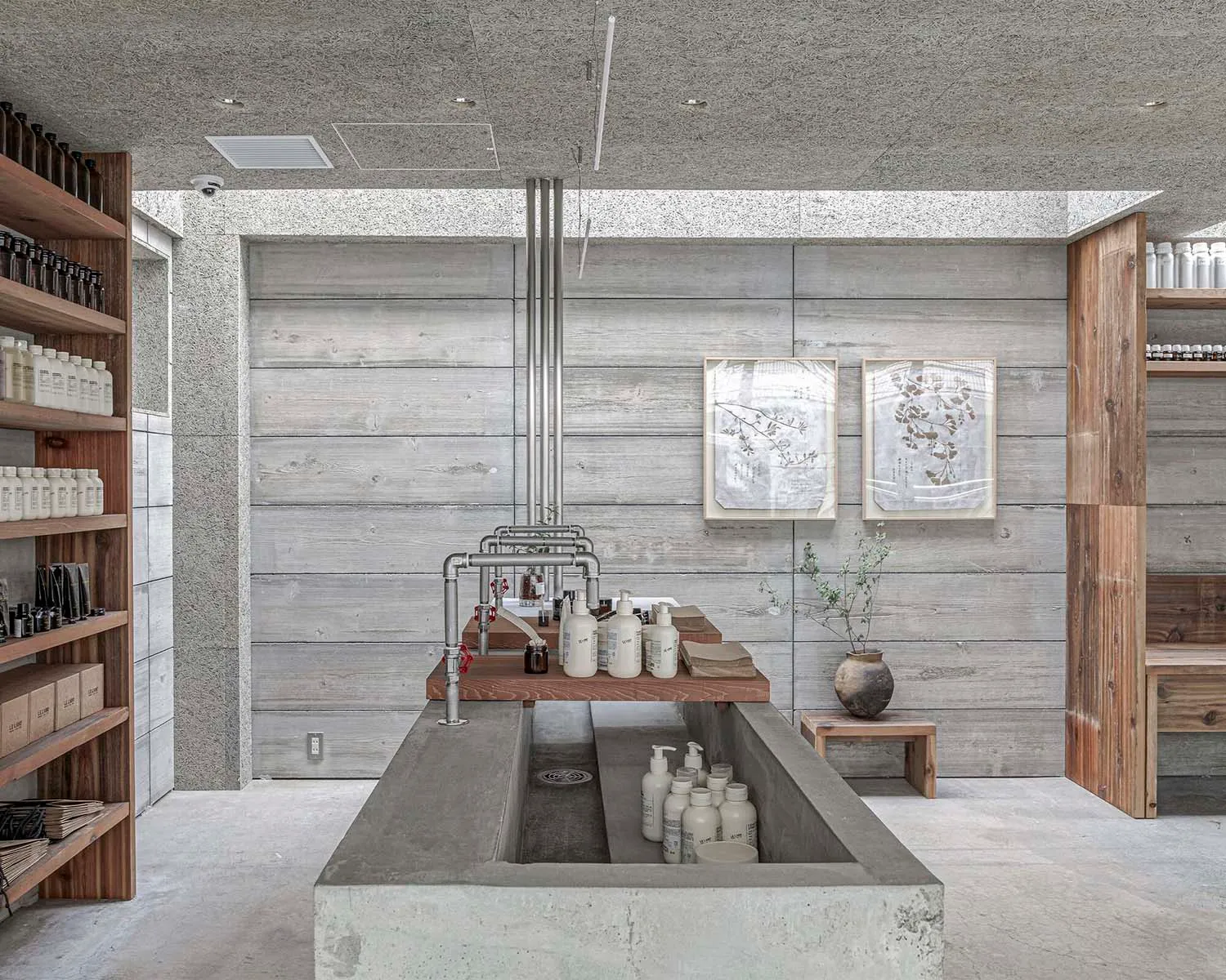 Bathroom with a concrete wall, sink area, and toiletries on the countertop, conveying a clean and organized atmosphere