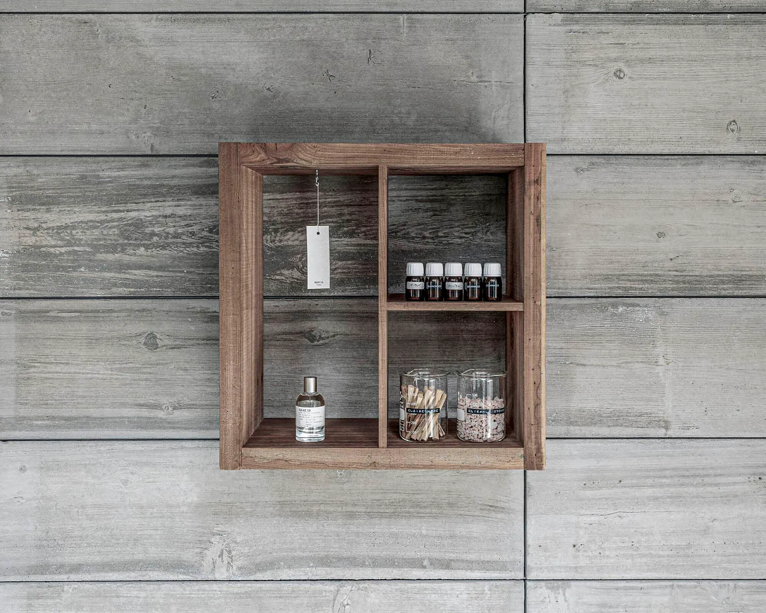 A wooden cabinet with bottles, cups, and a toothbrush holder, mounted on a wall for organized storage of personal care items