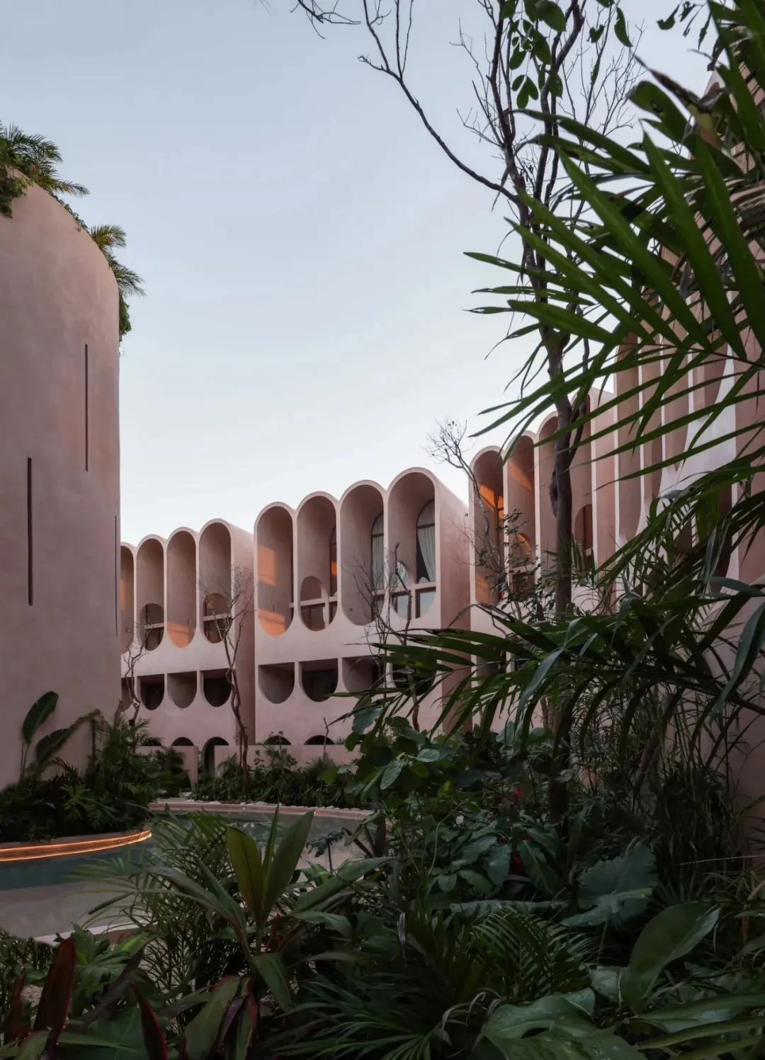 A large hotel building with a pink and white exterior, surrounded by palm trees, creating a tropical ambiance and inviting atmosphere