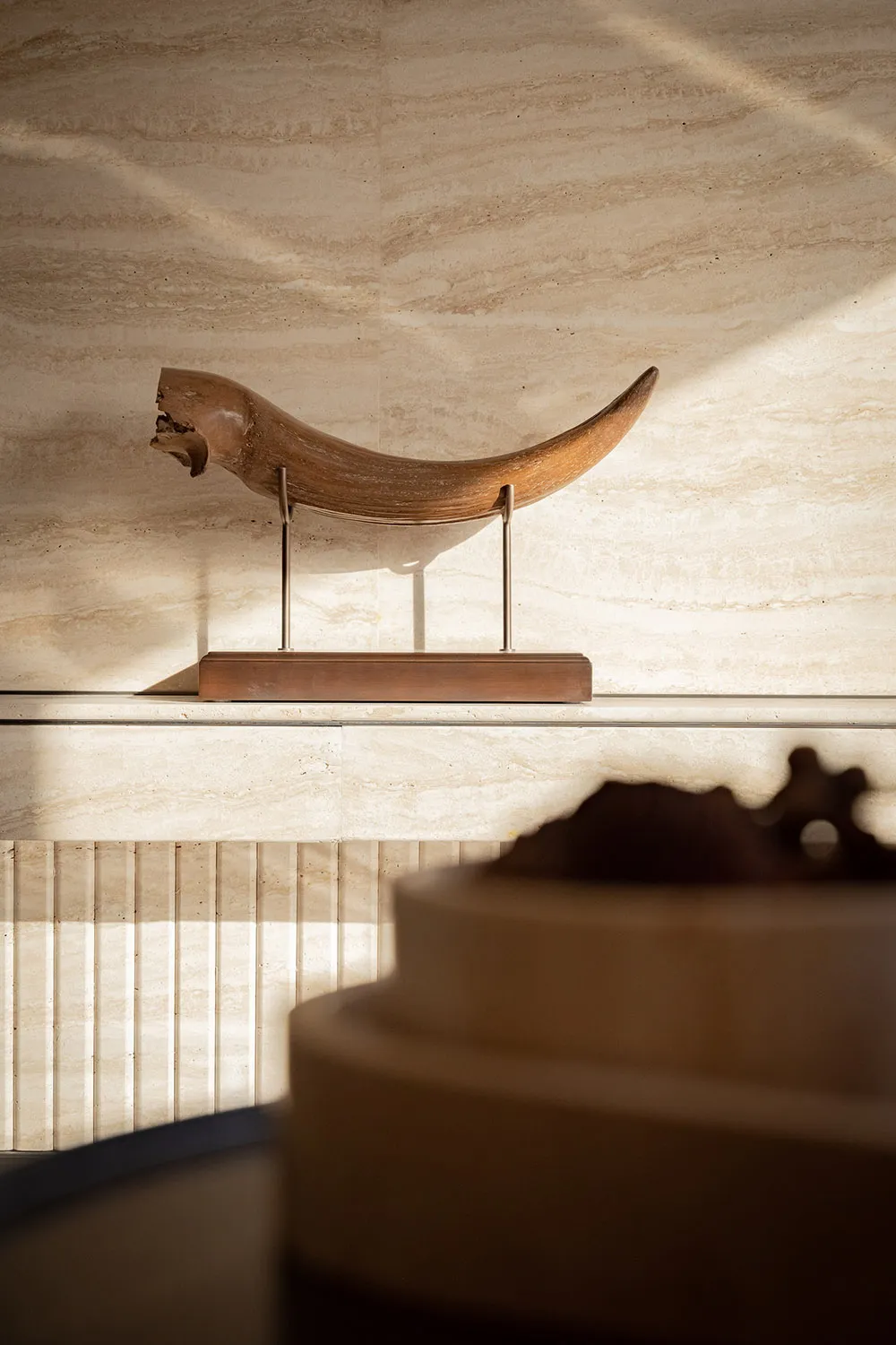 A wooden bull sculpture on a pedestal in a museum or gallery, surrounded by an atmosphere of art and creativity