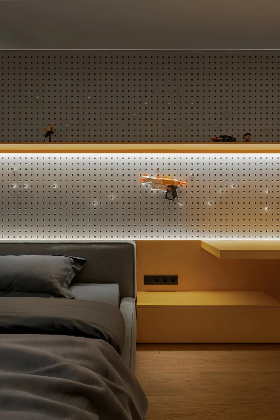 A casual bedroom with a bed, couch, and bulletin board featuring toys and objects, creating a comfortable atmosphere
