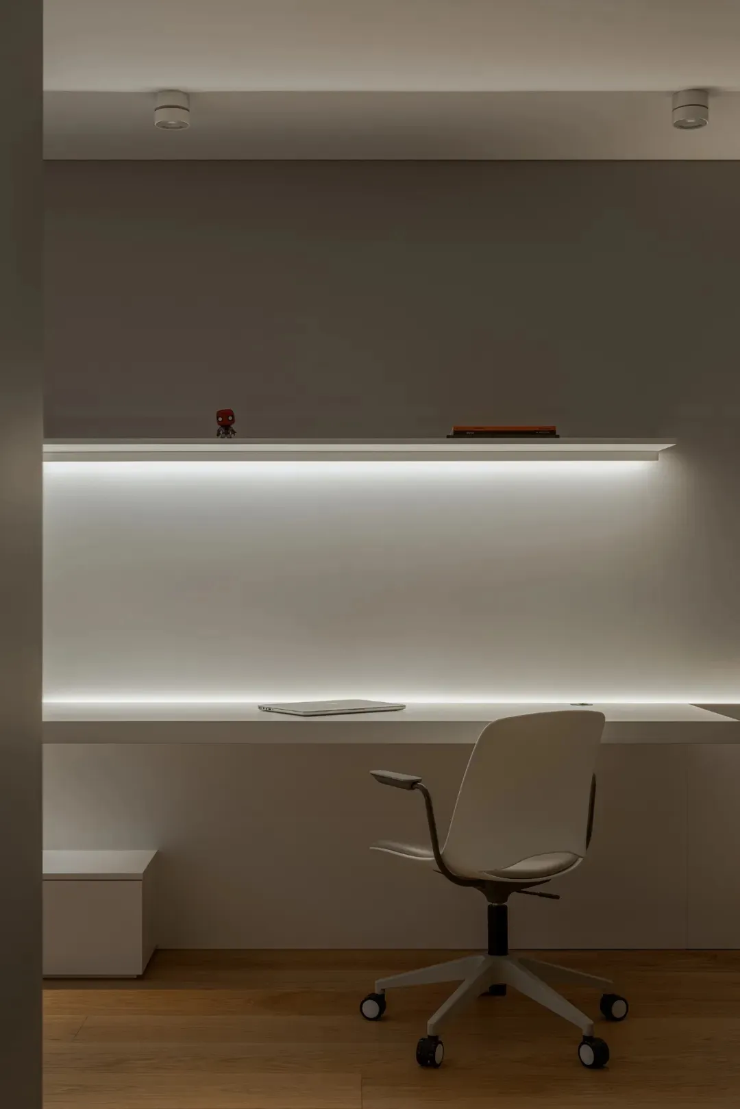 A professional office space with a white desk, two laptops, and three books, with a person partially visible in the background
