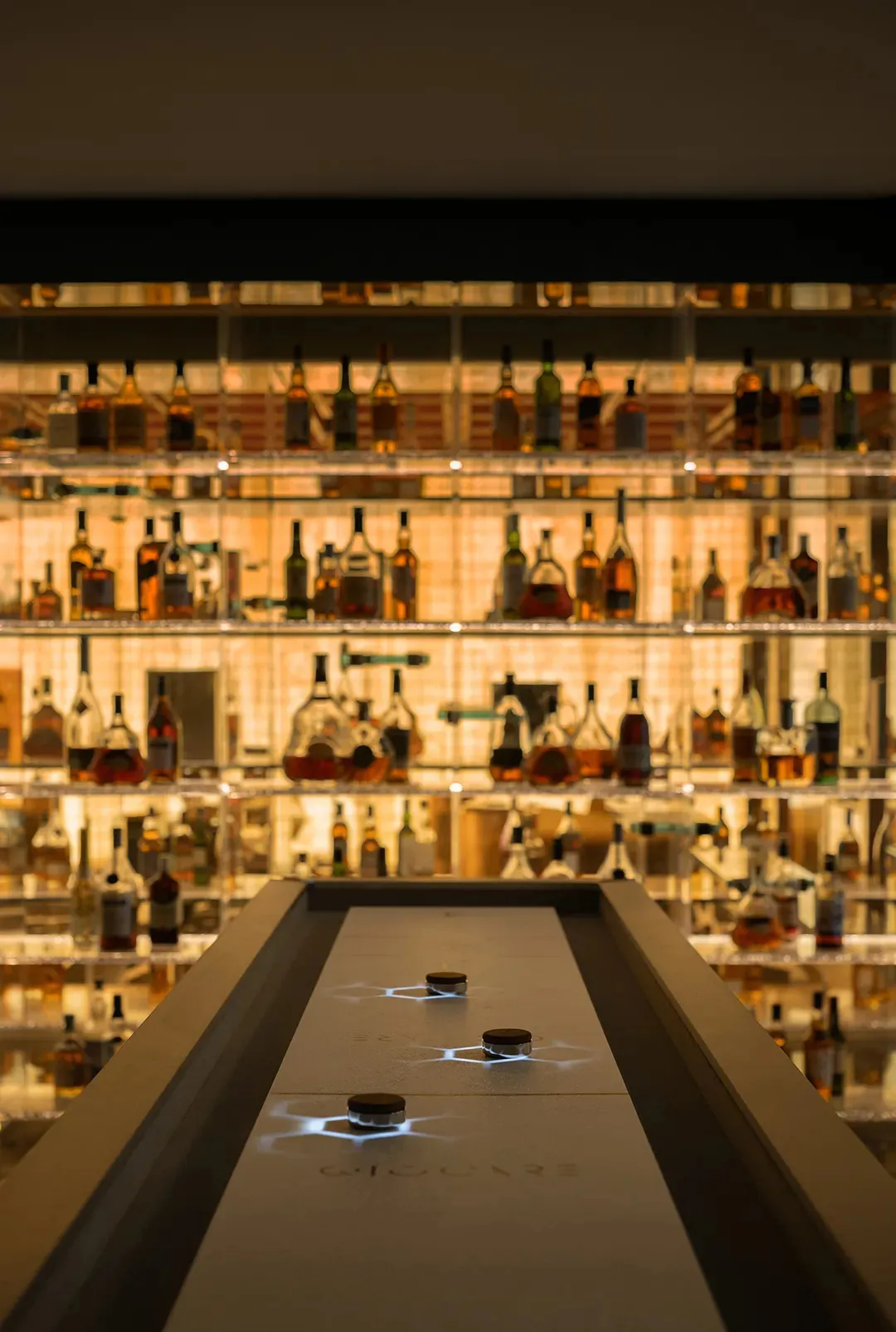 A bar filled with bottles of alcohol and wine glasses on a countertop, conveying elegance and a wide selection of drinks