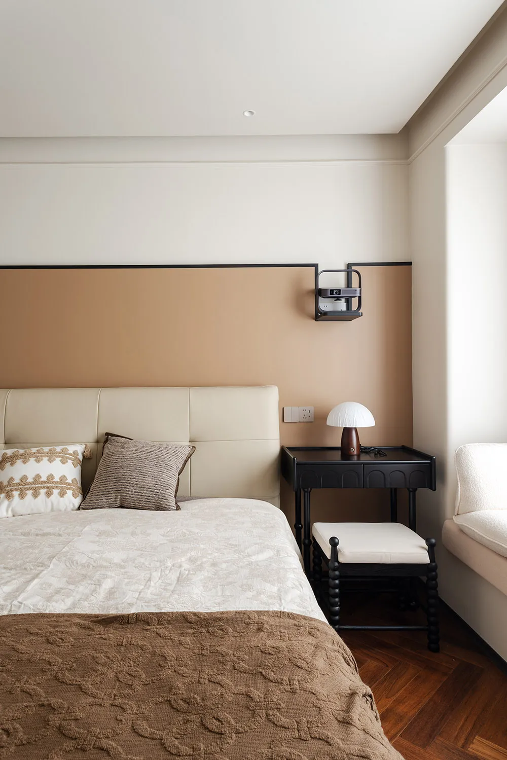 Cozy modern bedroom with a large bed on a beige carpet, two lamps, and a brown wall