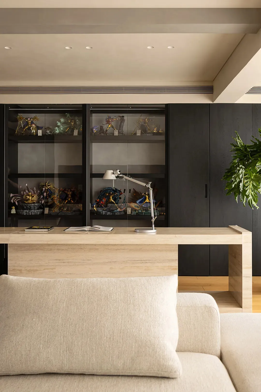 A functional office space with a desk, bookshelves, and a potted plant, featuring a mix of wood and other materials