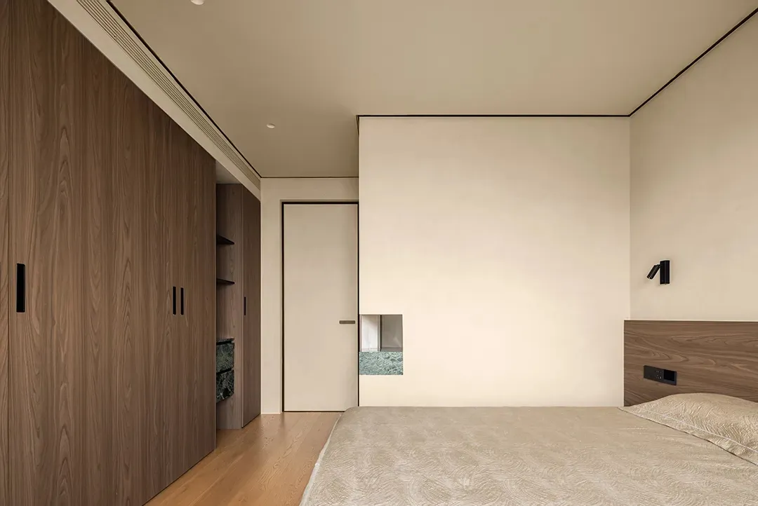 Empty minimalist bedroom with a large white wall, wooden floor, and two doors leading to other areas of the house