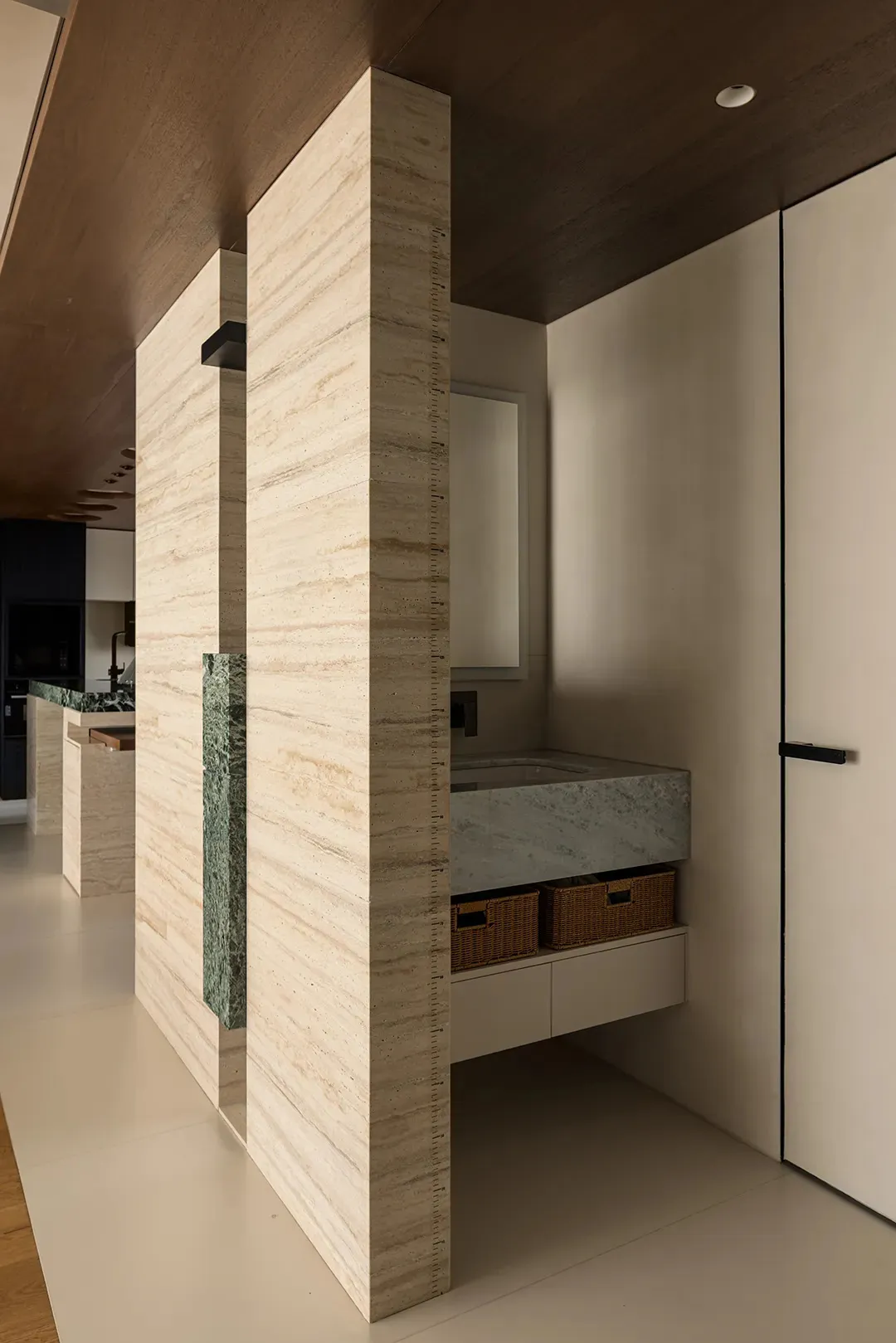Bathroom with marble walls, sink, mirror, and shower area, featuring modern and sophisticated design with warm and inviting lighting