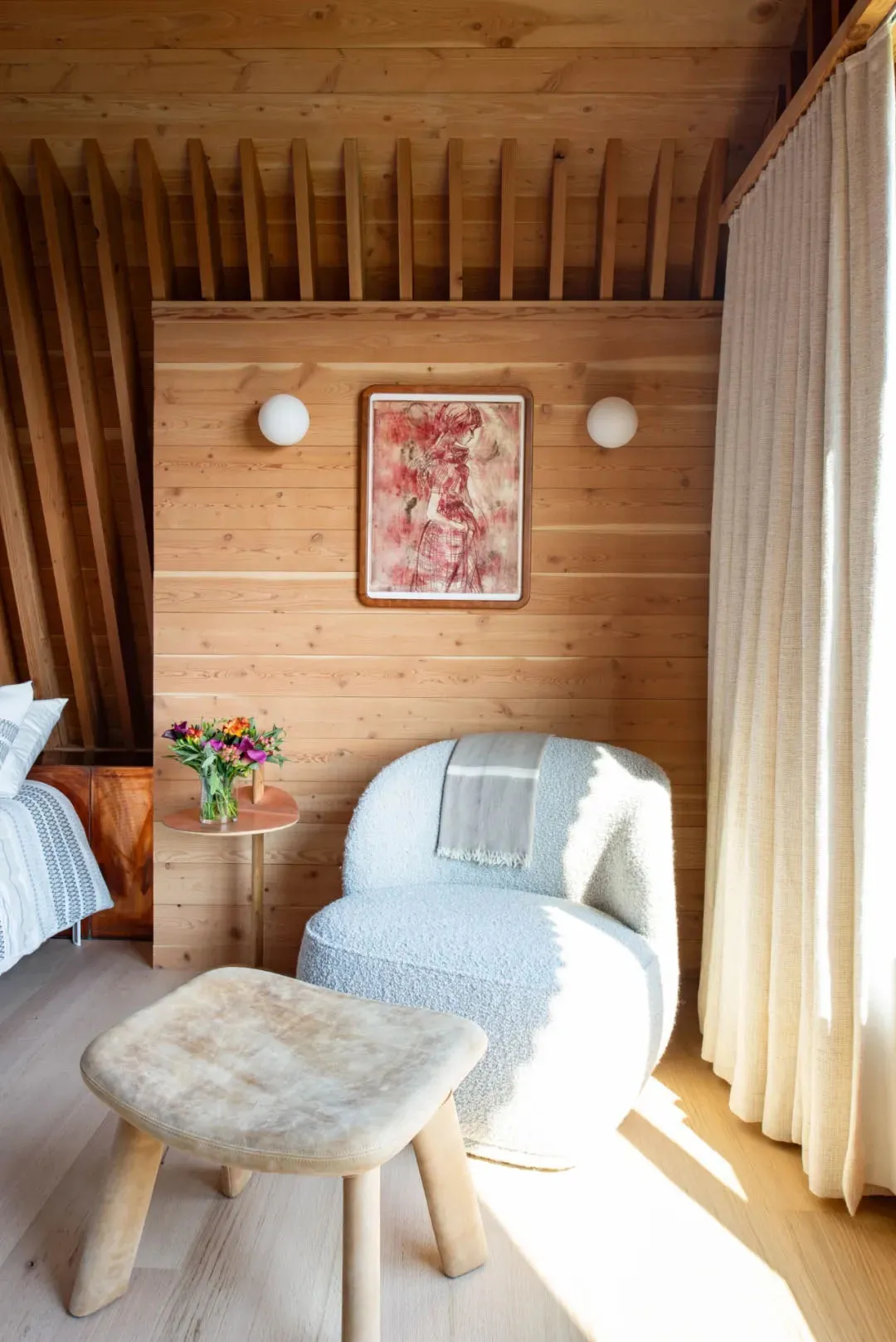 Warm and cozy living space with wooden walls and floors, featuring two chairs and a decorative vase on a table