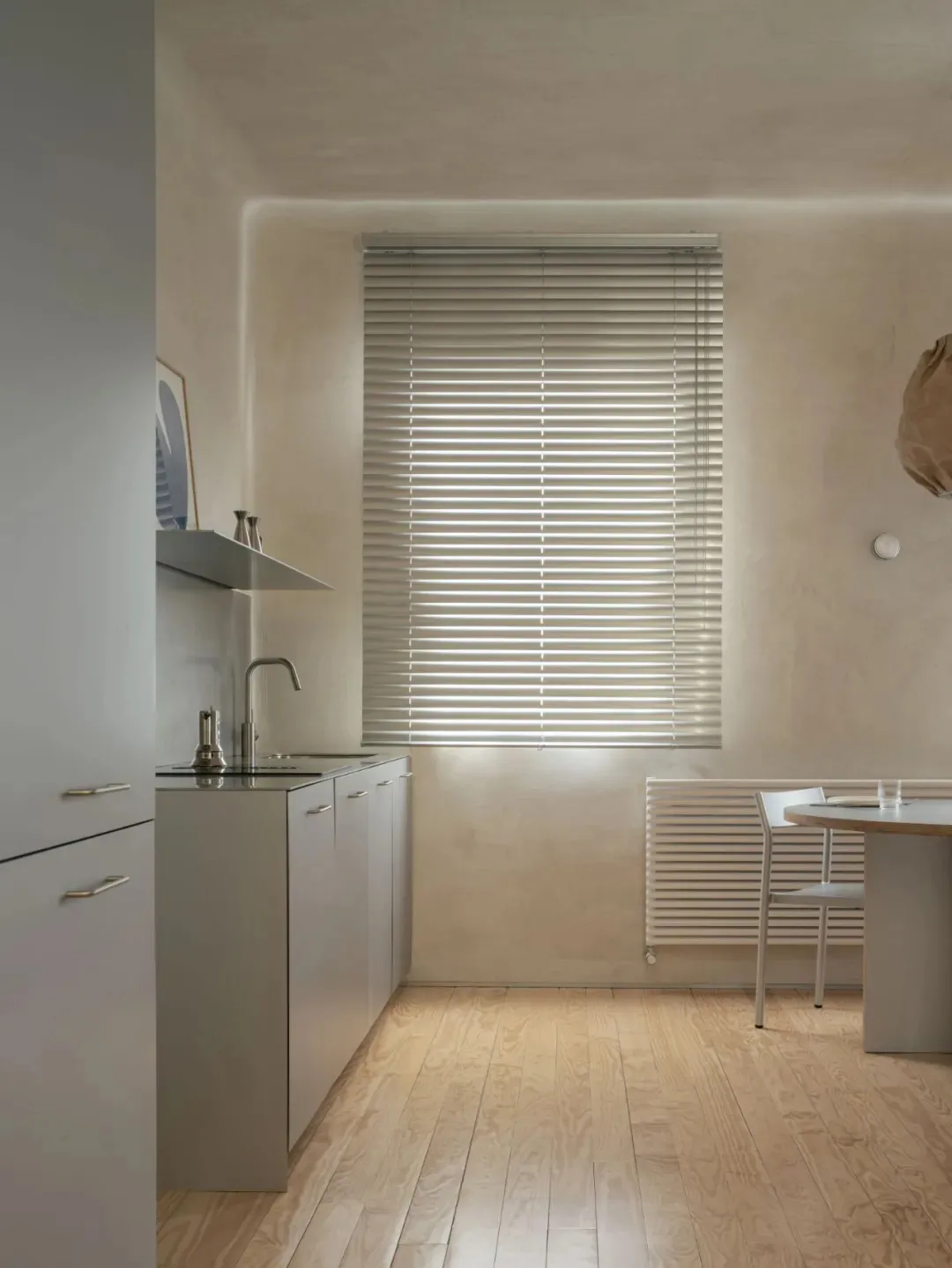 Modern kitchen and dining area with white walls, a table, chairs, and natural light from a window