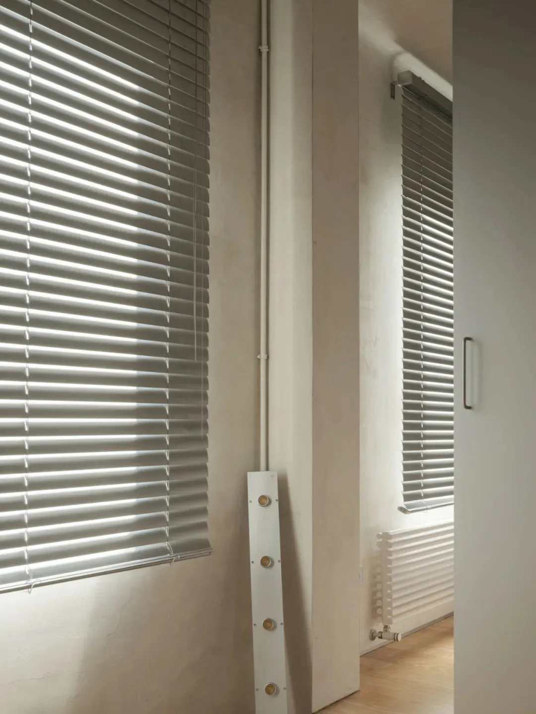 Interior room with white blinds, natural light, and a wall-mounted air conditioner unit