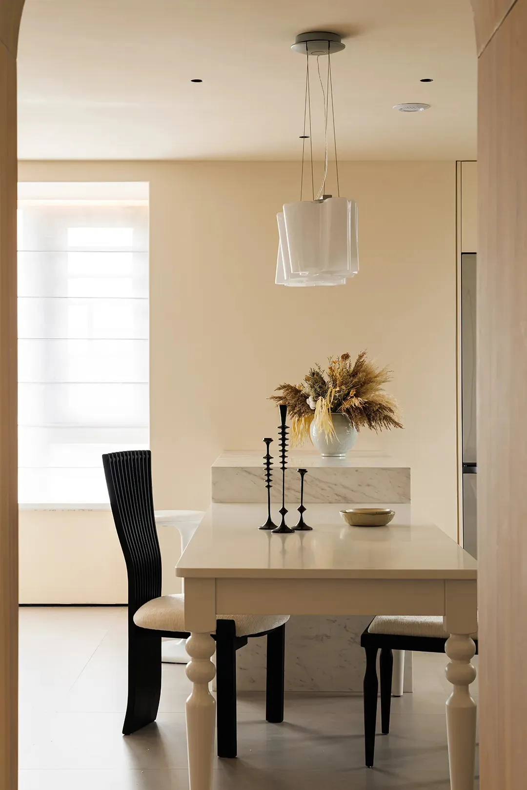 Dining area with a marble table surrounded by chairs, a kitchen area, and a vase adding a decorative touch