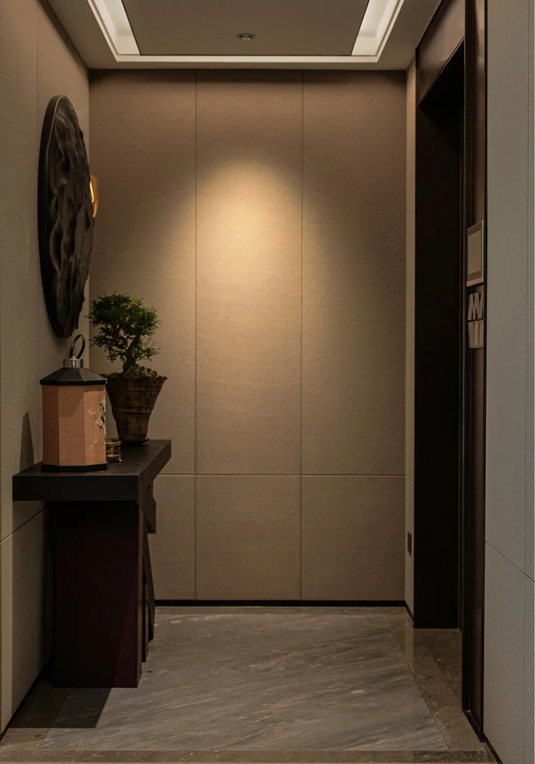 A well-lit interior hallway with a doorway and two potted plants on either side, adding greenery to the space