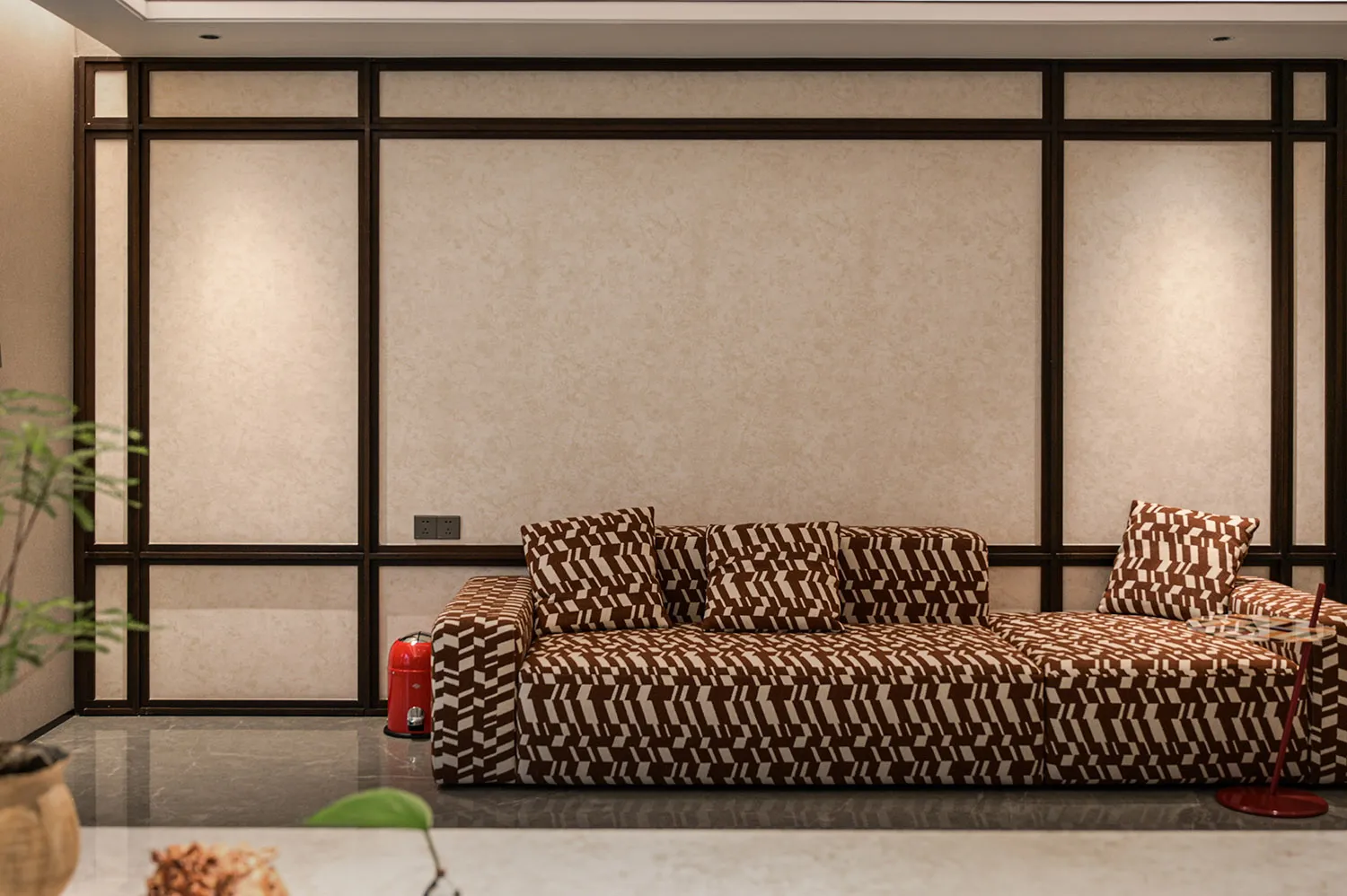 Cozy living room with a brown couch, zebra print pillows, and a potted plant on a hardwood floor, with a fire hydrant in the corner