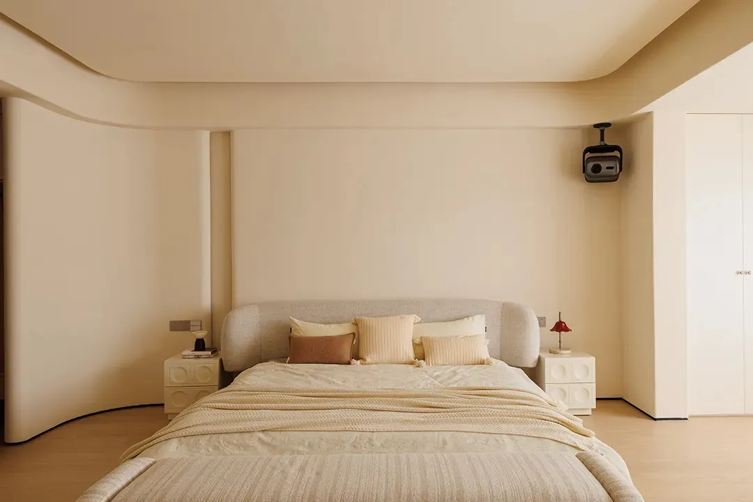 A cozy bedroom with a large white bed on a beige carpet, lit by two lamps, creating a relaxing atmosphere