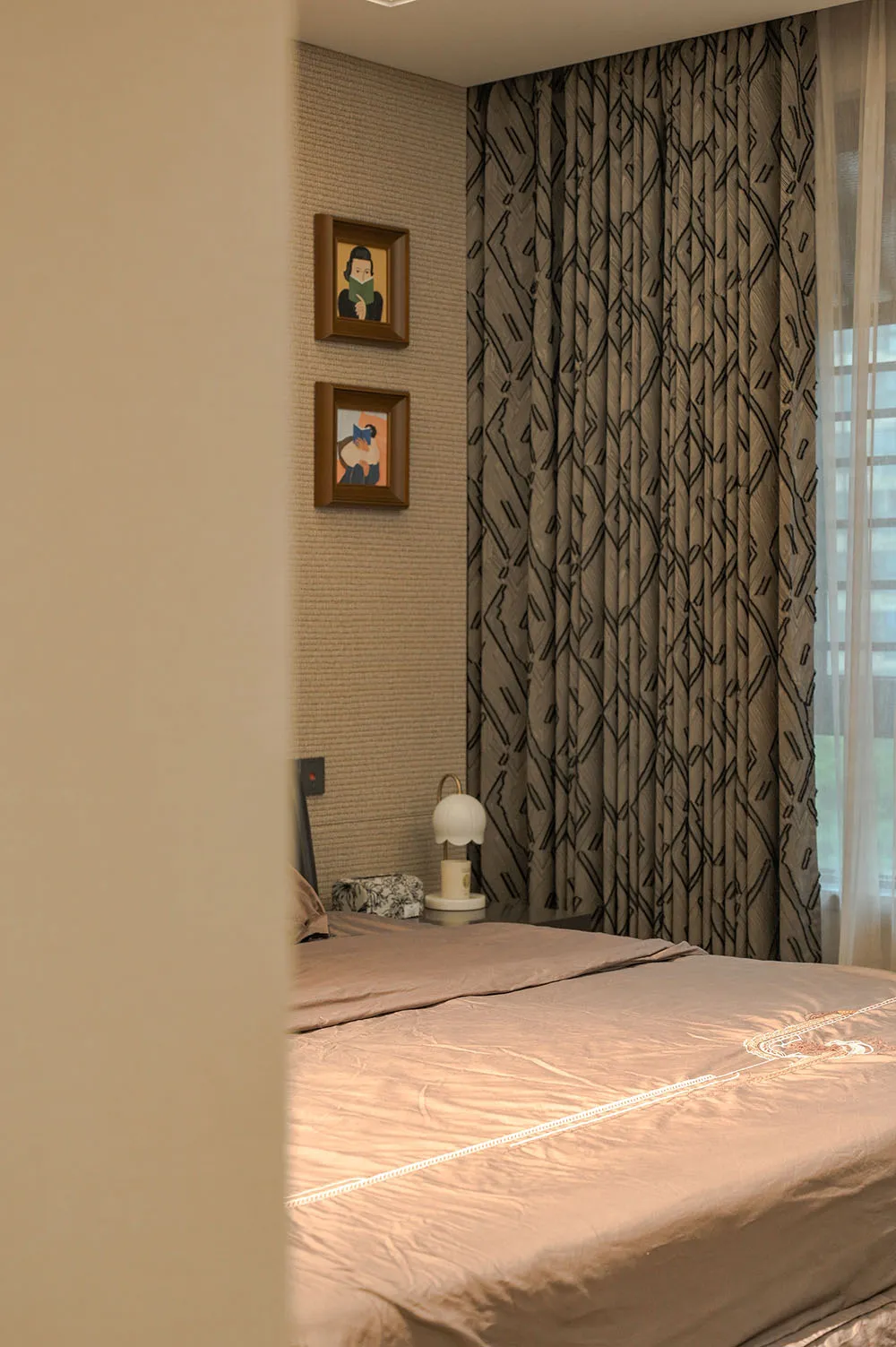 A well-lit bedroom with a large bed, two pictures on the wall, and a lamp for reading, creating a cozy and inviting atmosphere