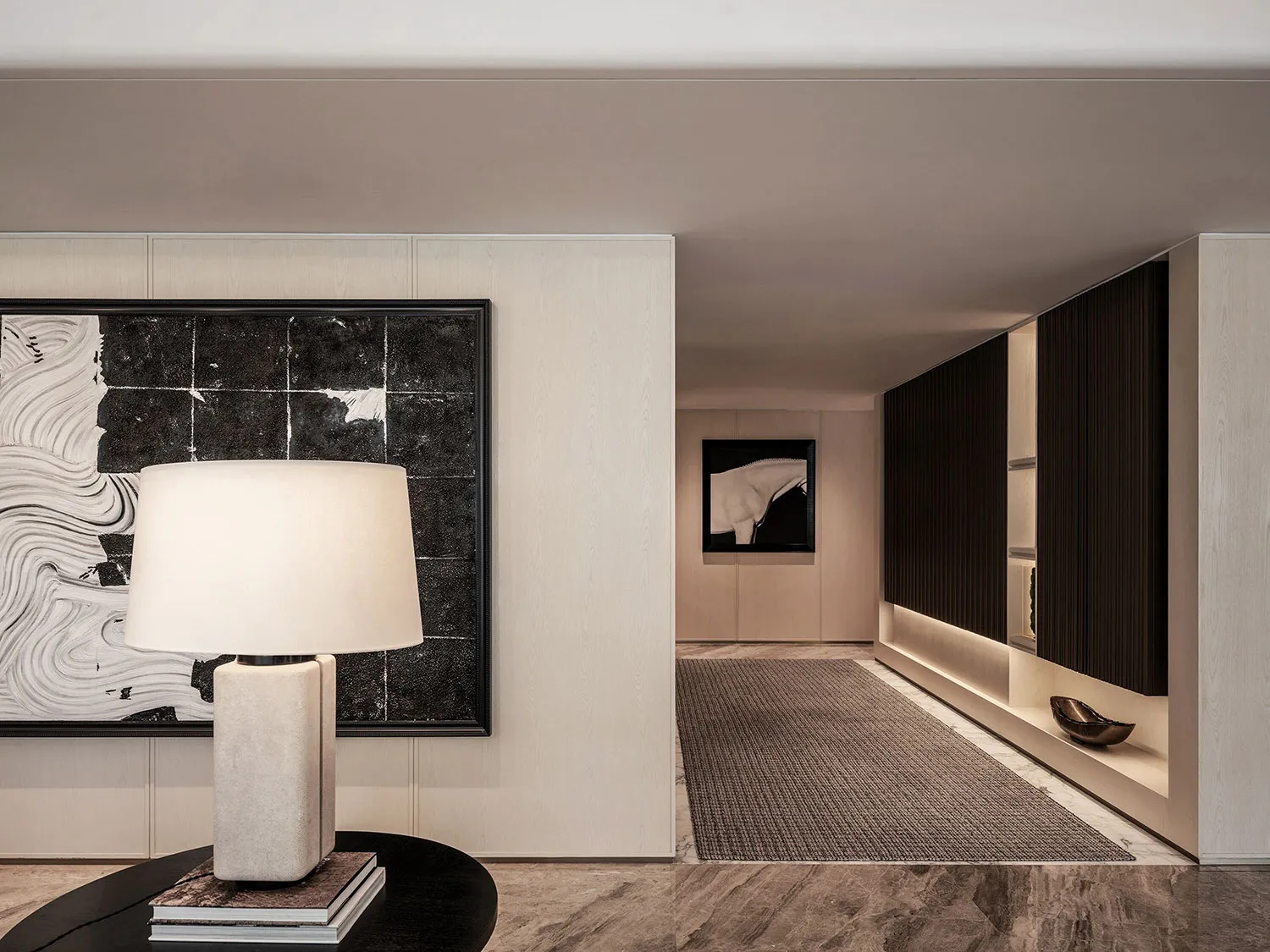 Empty modern hallway with white walls and flooring, featuring two framed pictures and a central lamp