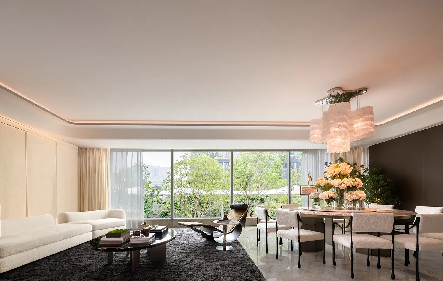 Sophisticated living room with two couches, chairs, a dining table, and vases, filled with natural light from a large window