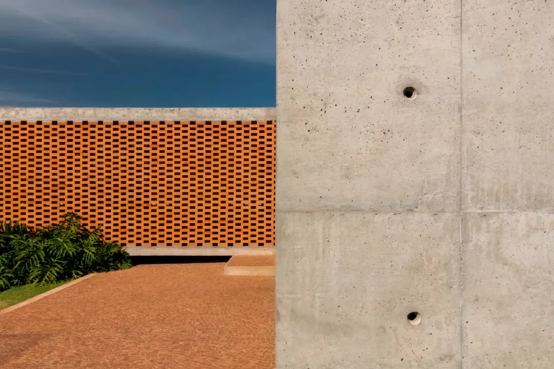 A large building with a red brick wall and a concrete structure, blending traditional and modern architectural elements