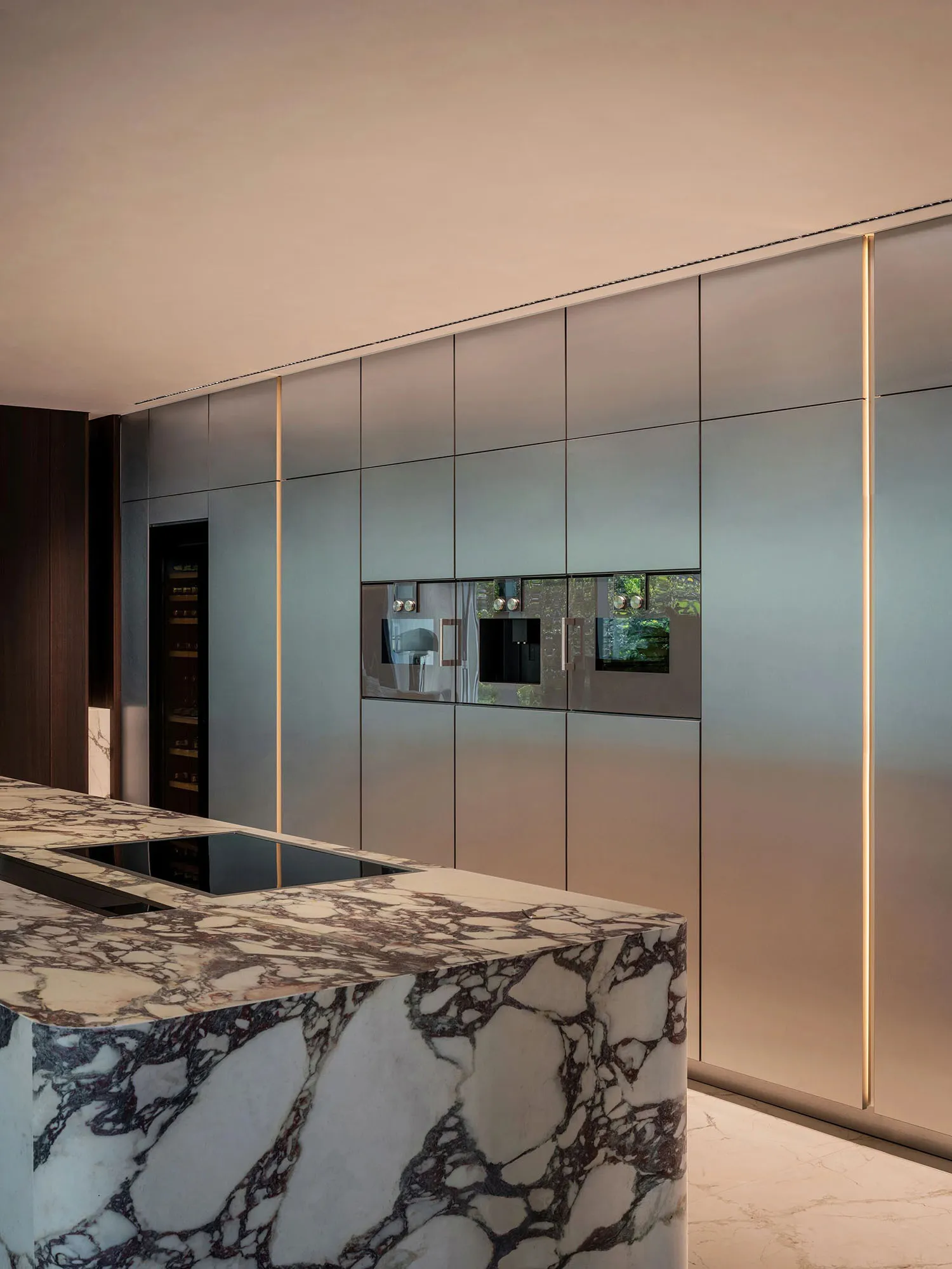 Well-lit kitchen with marble countertops, stainless steel appliances, and bottles on the countertop