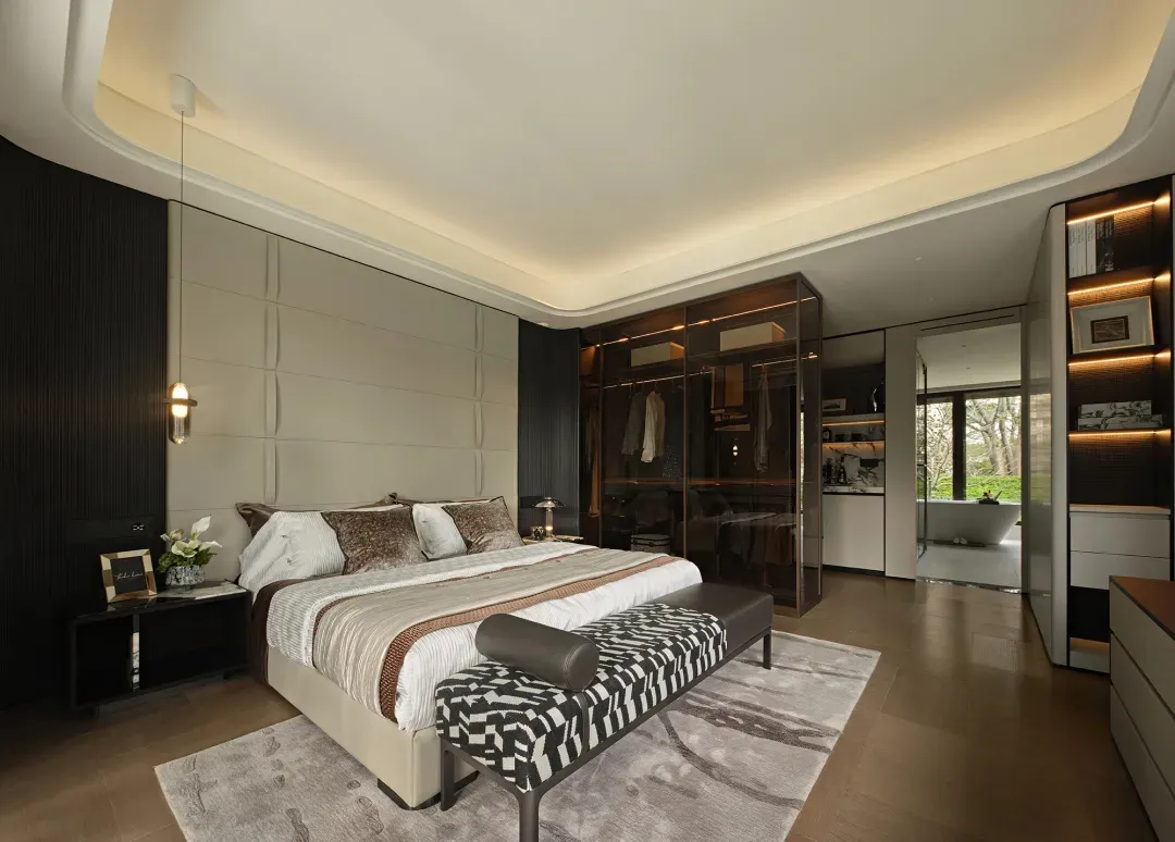 Spacious bedroom with a brown and white comforter, two couches, chairs, a dresser, and a dining table, creating a cozy and inviting atmosphere with neutral tones and earthy hues