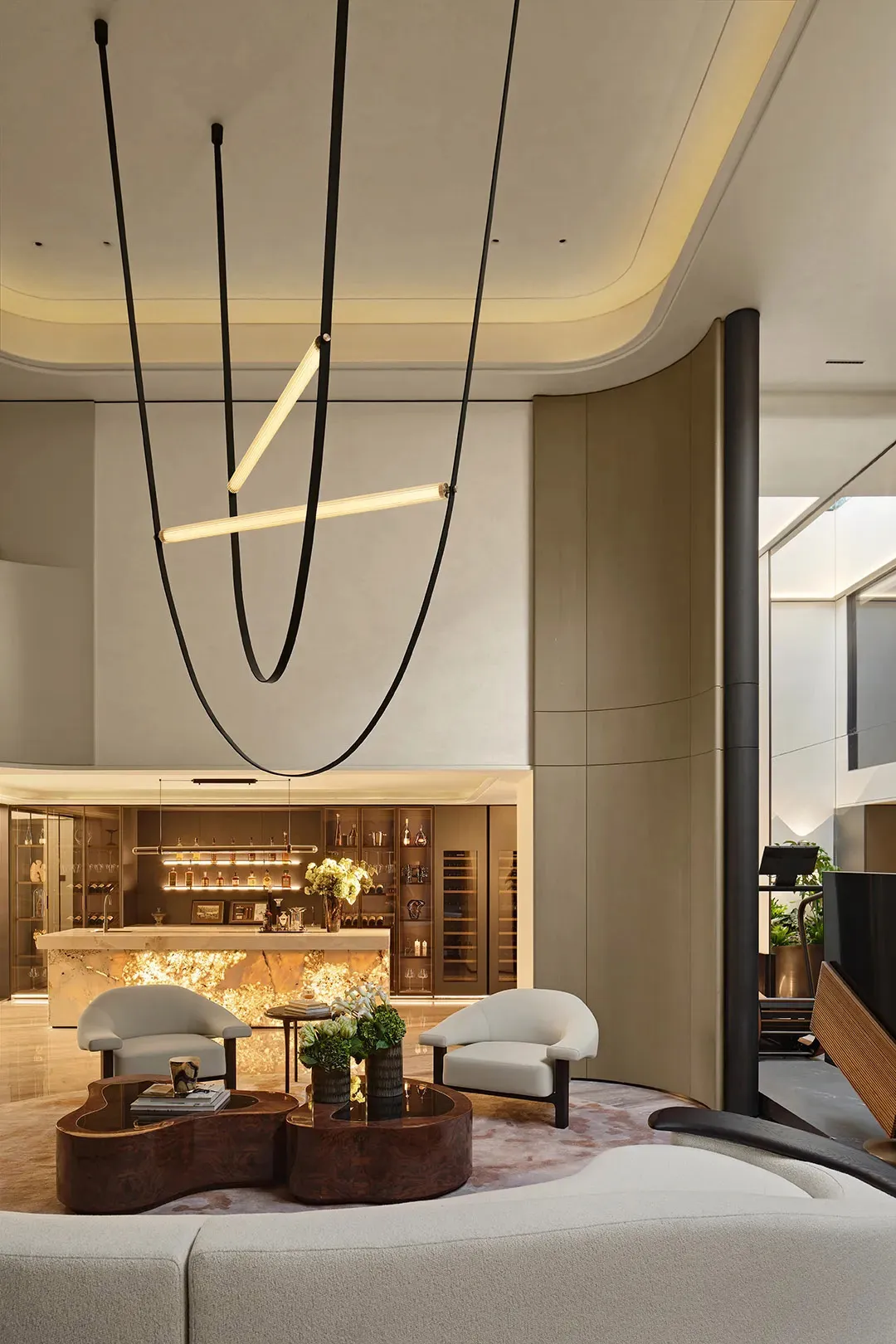 A modern dining space with a chandelier, potted plants, a couch, and wine glasses on the table