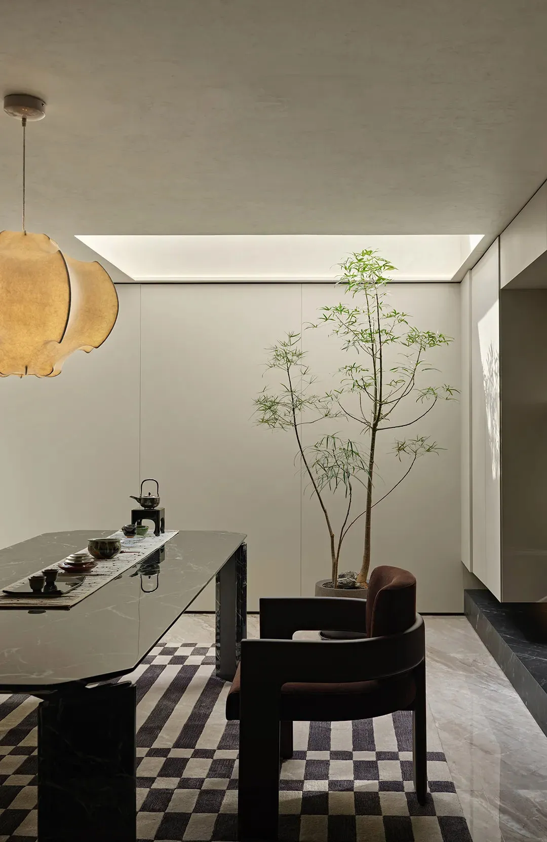 A well-lit living area with a dining table, chairs, a potted plant, and a vase, creating a comfortable atmosphere for socializing and enjoying meals