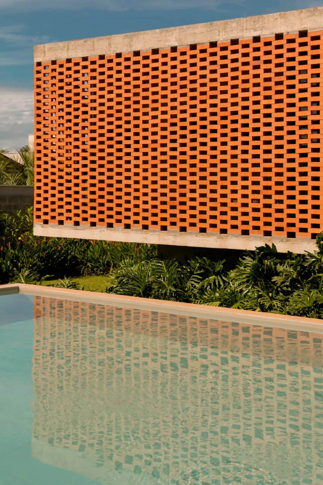 A photo of an orange wall with a pattern of squares, surrounded by potted plants in a relaxing and inviting environment